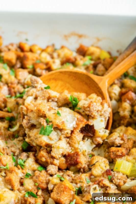 Savory Sausage Mix 3 A serving spoon lifting a scoop of moist, flavorful sausage stuffing from a baking dish.