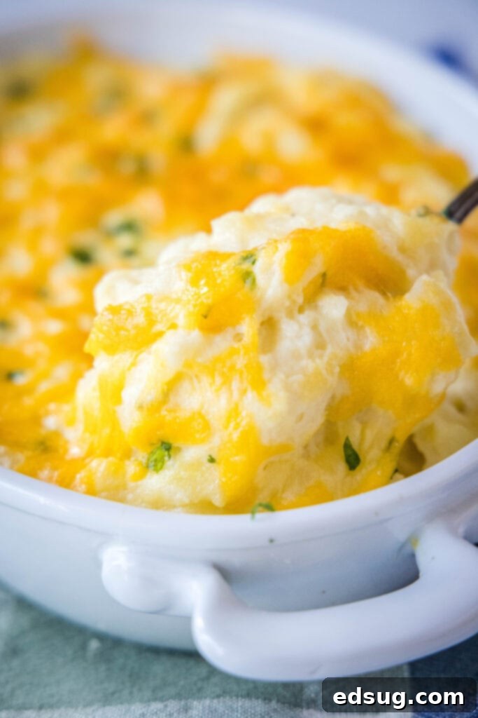 Ultimate Cheesy Mashed Potatoes 2 spooning out cheddar mashed potatoes from baking dish