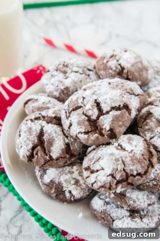 Snow-Dusted Chocolate Crinkles 3 A close up of a plate overflowing with chocolate crinkle cookies, dusted with powdered sugar