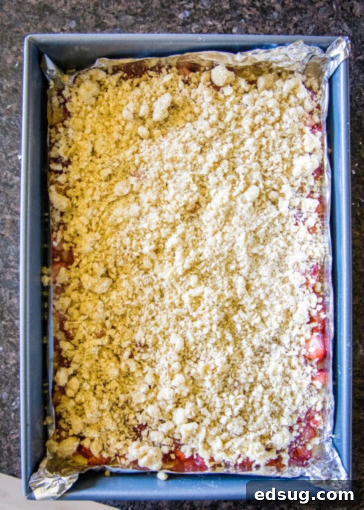 adding crumb topping to strawberry bars before baking