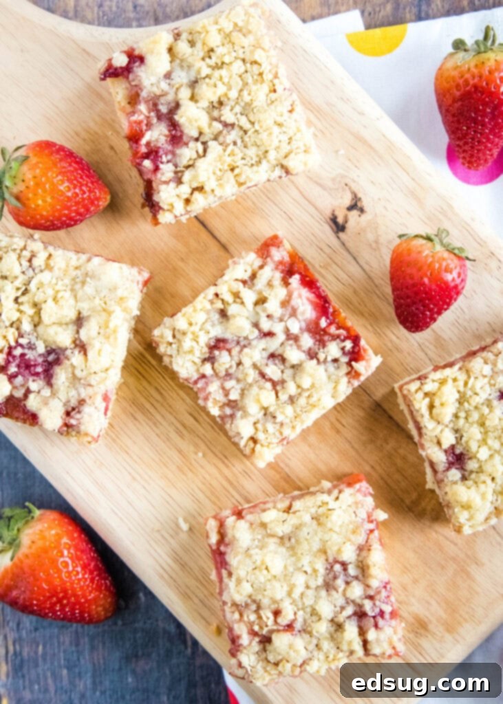 overhead shot of strawberry crumb bars on a cutting board, ready to be sliced