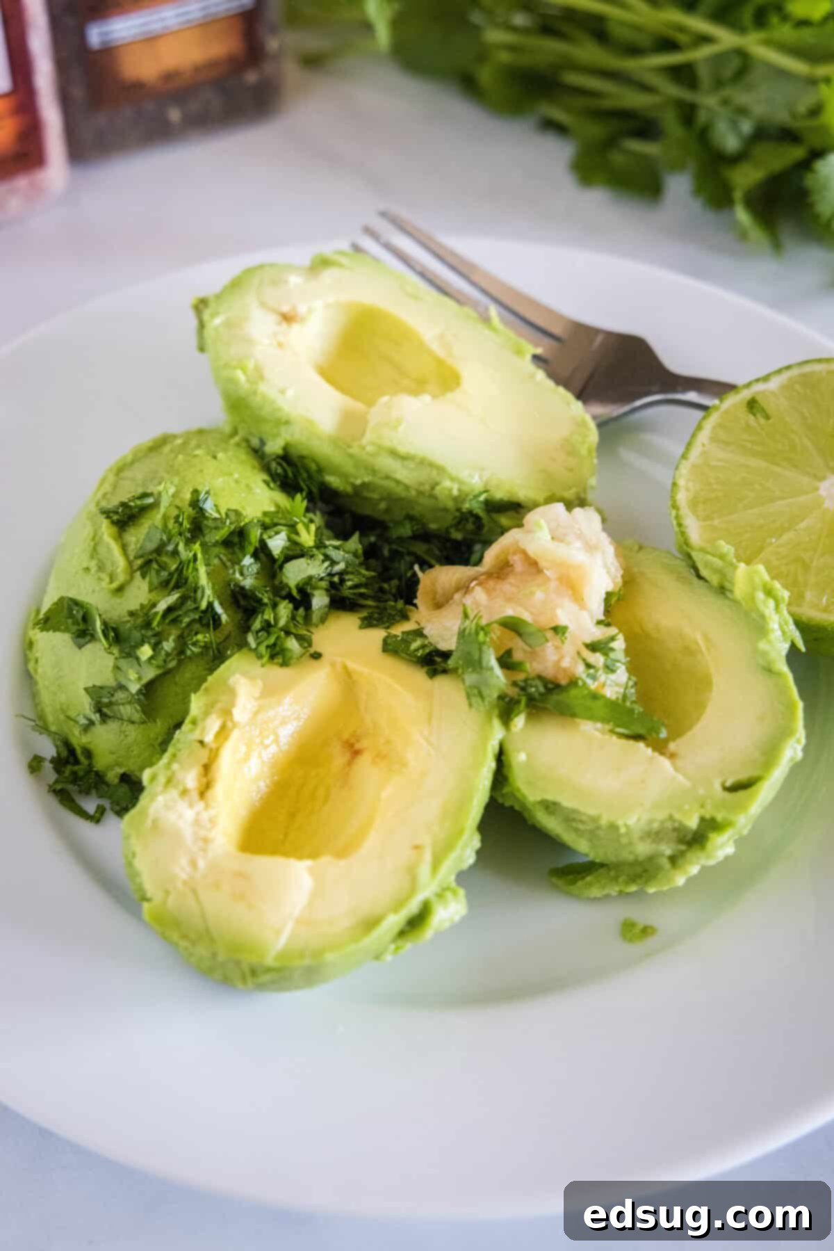 Smoky Garlic Guac Perfection 4 Ingredients for roasted garlic guacamole laid out on a plate, including mashed avocado, fresh lime wedges, chopped cilantro, and a small pile of golden roasted garlic paste, ready to be combined.