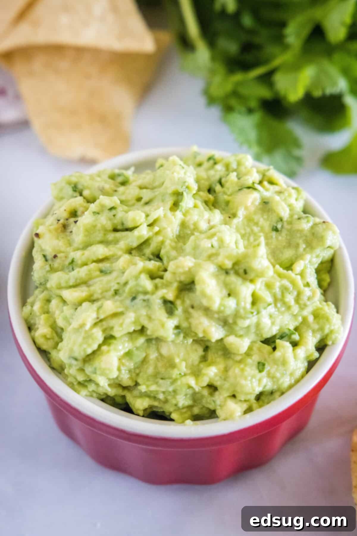 Smoky Garlic Guac Perfection 6 A large, inviting ceramic bowl of roasted garlic guacamole, topped with fresh cilantro, ready to be served and enjoyed at a gathering.