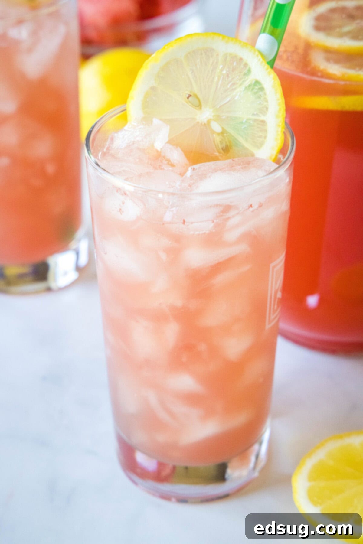 Sunny Watermelon Lemonade 6 A close-up of a glass of watermelon lemonade with ice, garnished with a watermelon slice and mint.