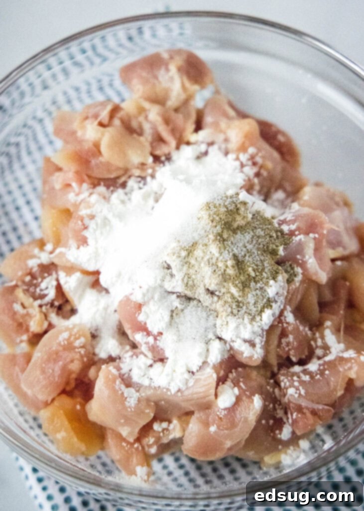 Savory Cashew Chicken Stir-Fry 4 adding cornstarch, salt, and pepper to cubed chicken in a mixing bowl for tenderizing