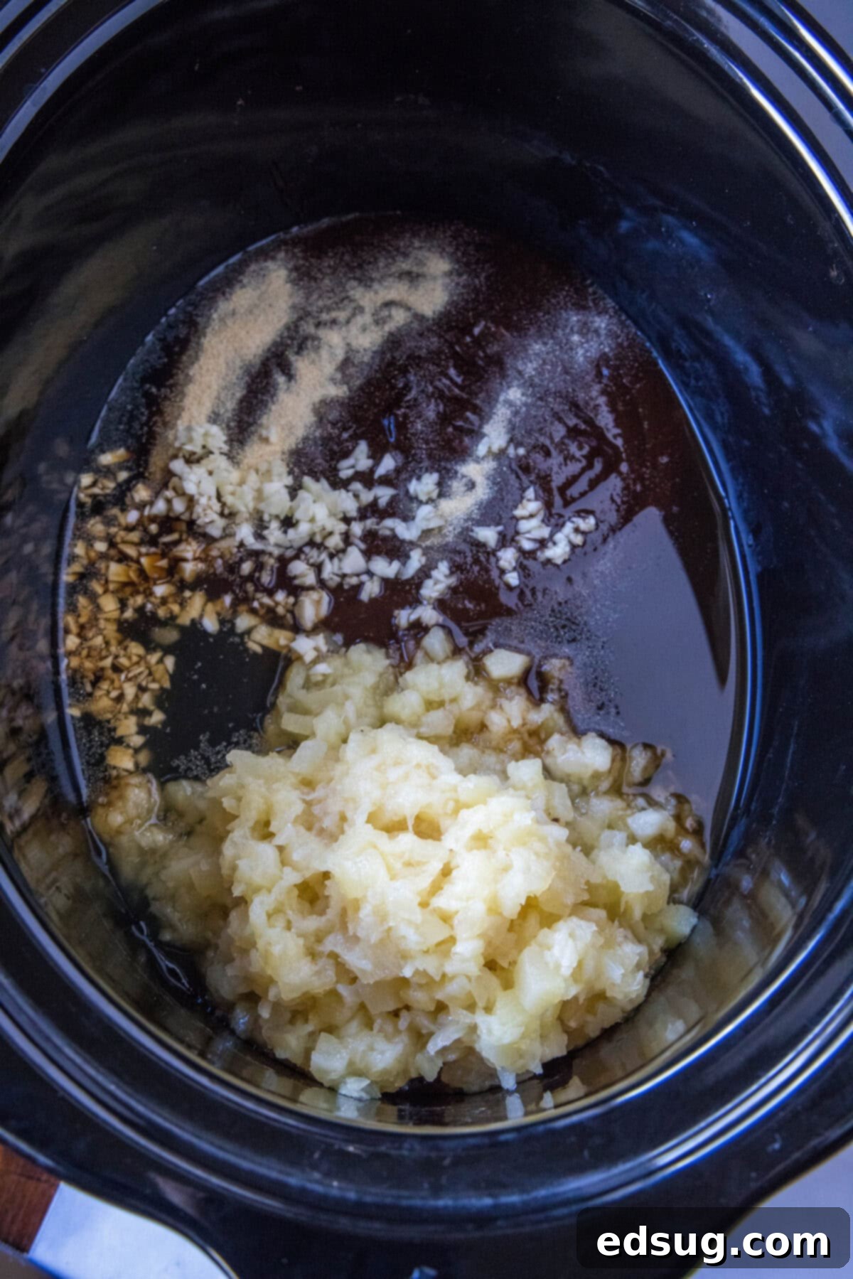 Close-up of the vibrant cooking sauce ingredients, including crushed pineapple and BBQ sauce, perfectly combined in the slow cooker insert.