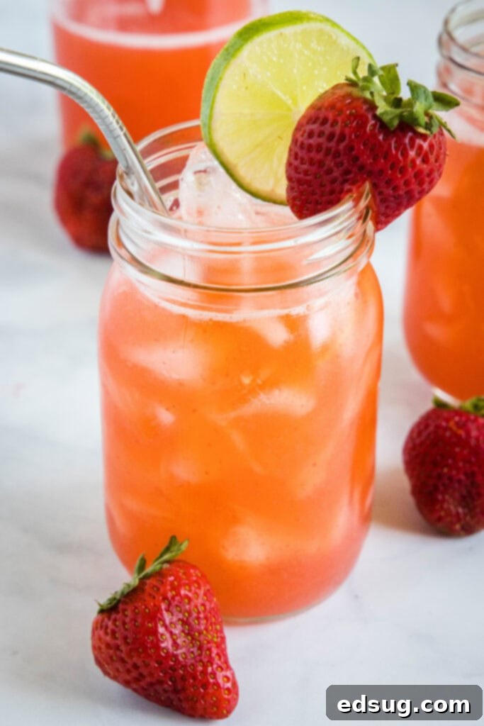 A chilled glass of homemade strawberry agua fresca in a mason jar, garnished with a lime slice and a fresh strawberry, ready to be enjoyed on a hot summer day.