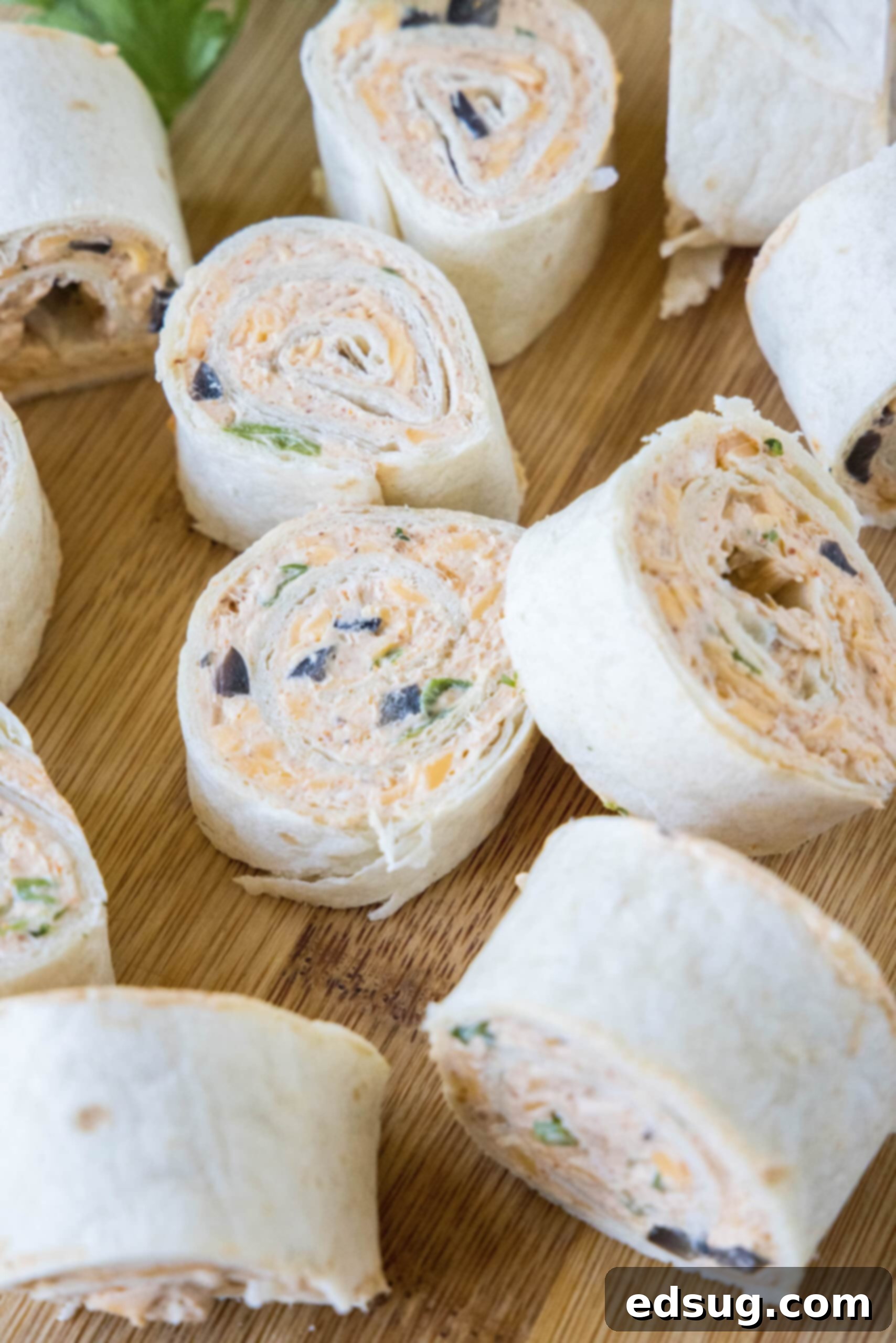 A close-up shot of perfectly sliced taco pinwheels arranged on a wooden cutting board, showcasing the colorful filling.