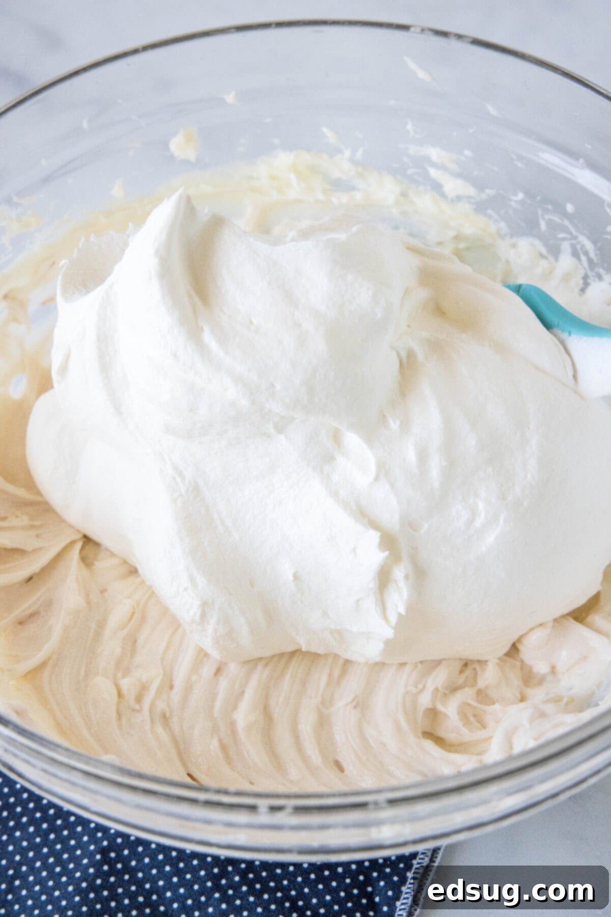 Whipped cream added to a bowl of whipped cream cheese.
