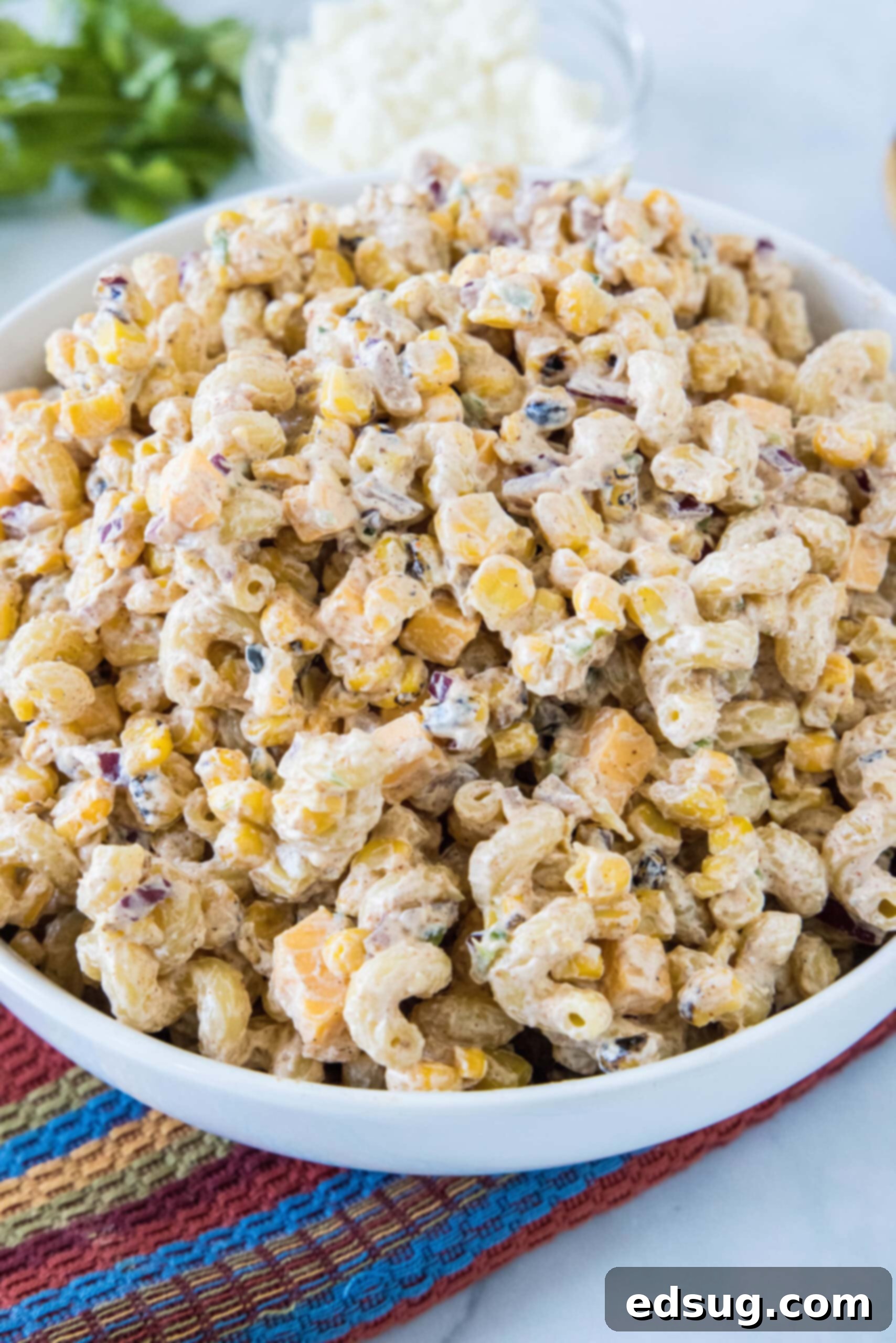 A large bowl filled with Mexican street corn pasta salad, garnished with cilantro and Cotija cheese, ready to be served.