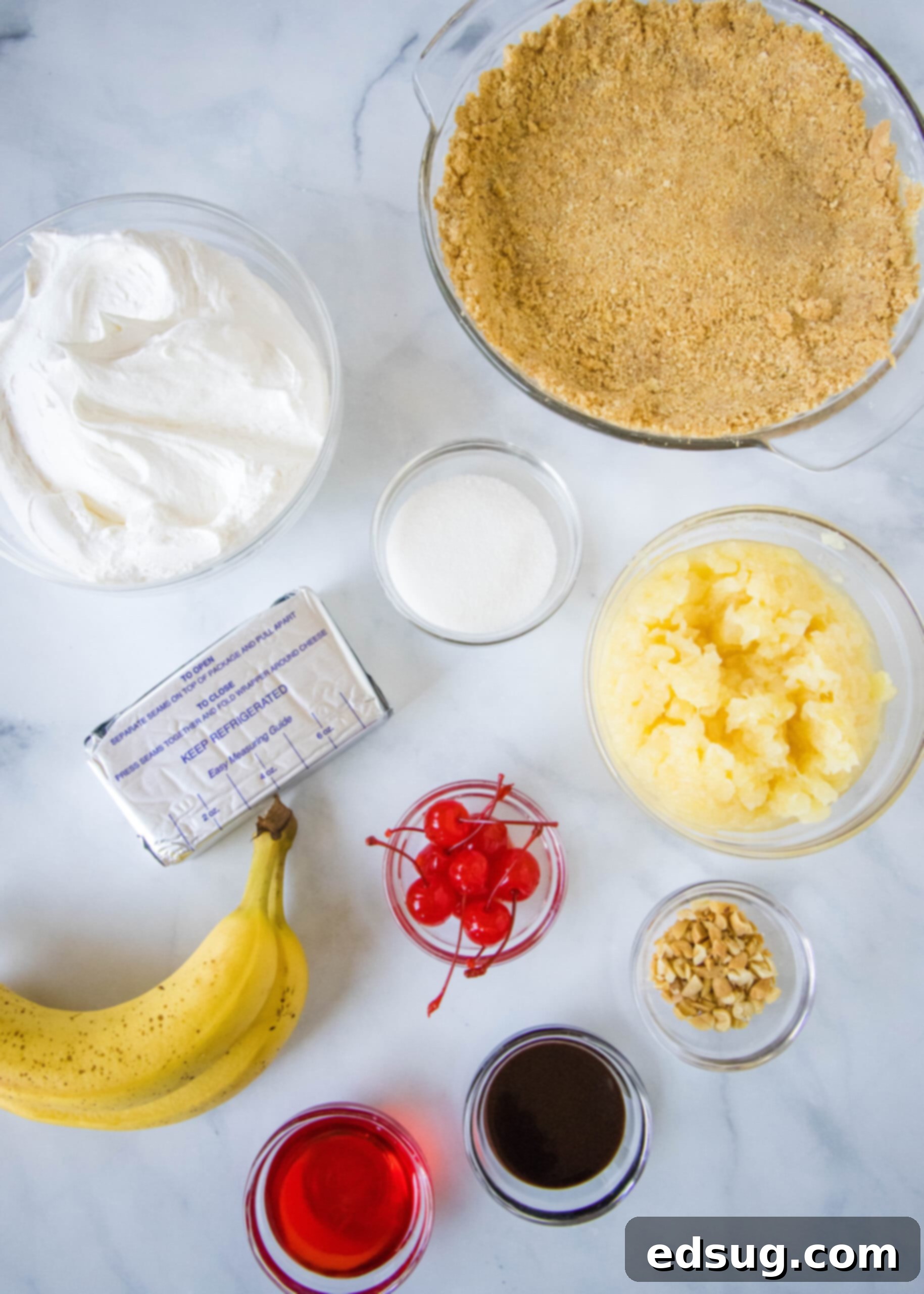 Banana split pie is a cool and creamy no-bake dessert that you can make in 20 minutes. Filled with whipped cream, bananas, and pineapple! A vibrant flat lay shot displaying all the fresh and packaged ingredients required to make a delicious banana split pie, neatly arranged on a kitchen counter.