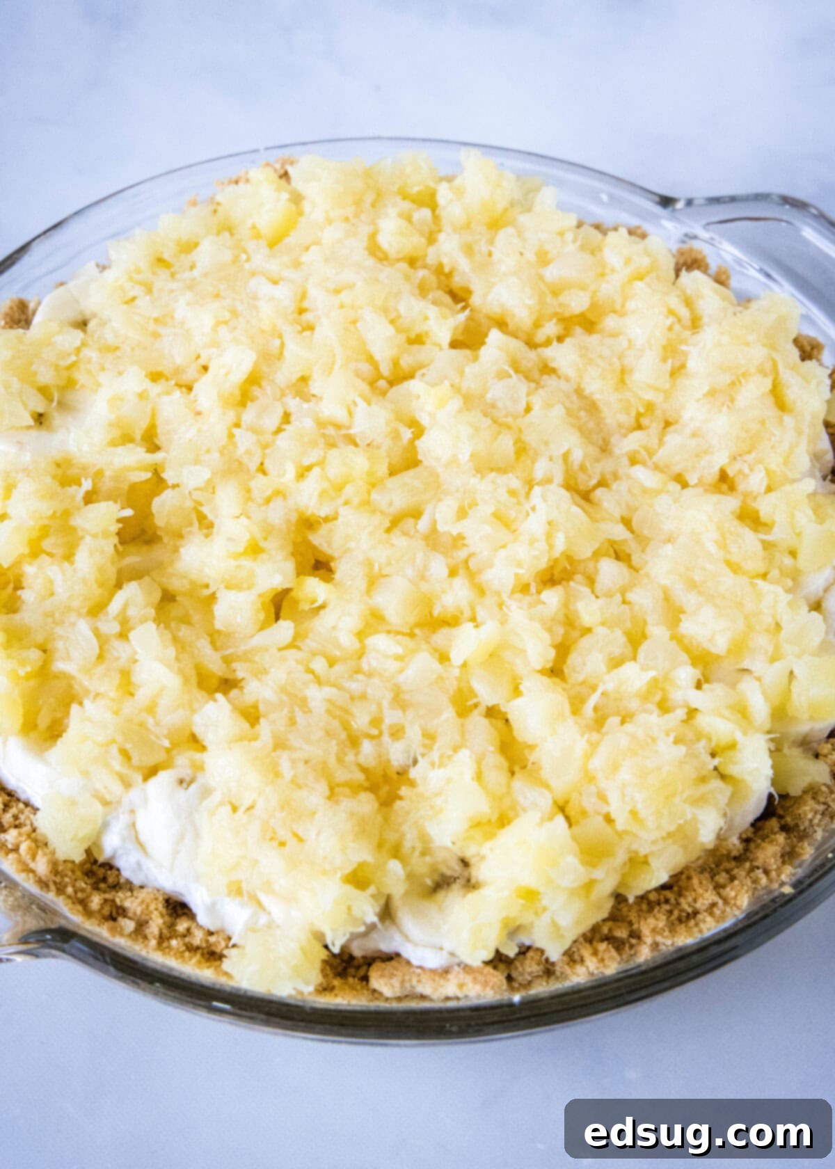 Banana split pie is a cool and creamy no-bake dessert that you can make in 20 minutes. Filled with whipped cream, bananas, and pineapple! Finely crushed pineapple, meticulously drained, spread in an even layer over the fresh banana slices, creating the next vibrant layer of the banana split pie.
