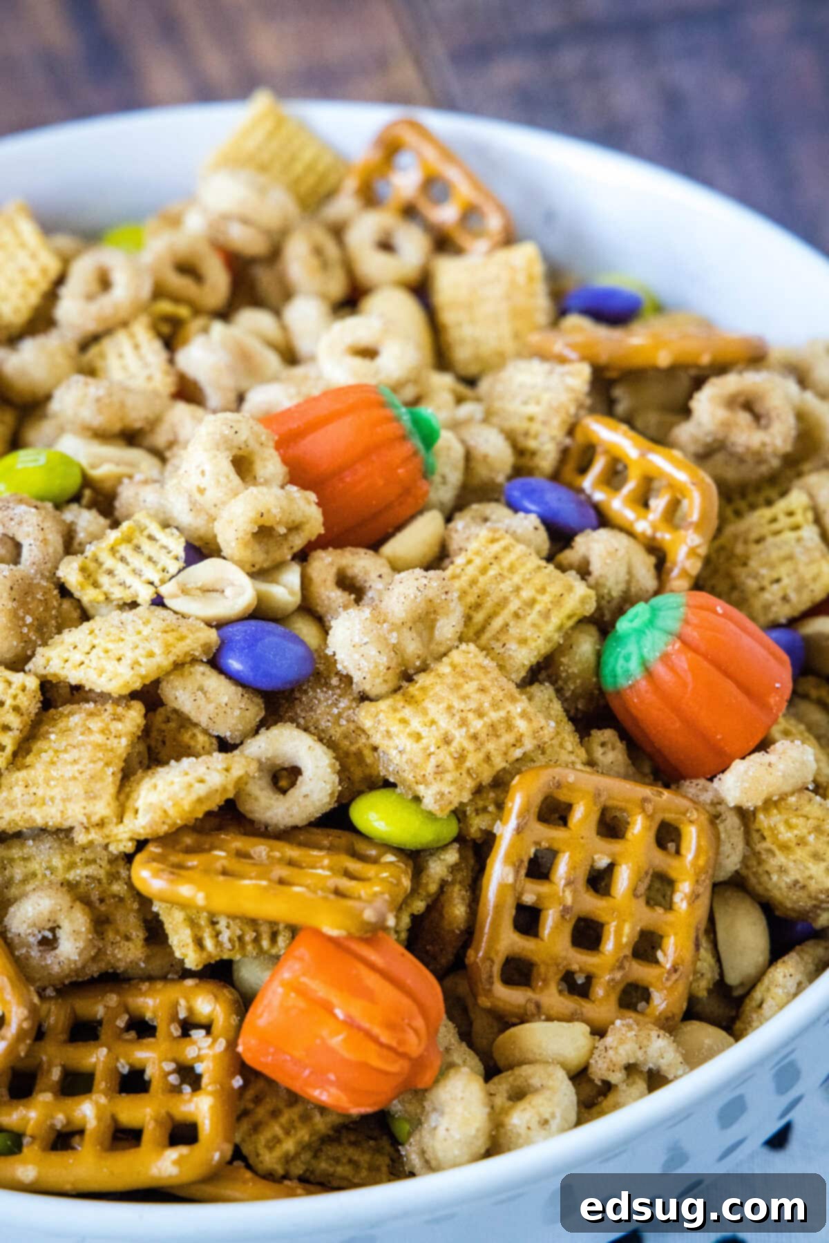Cozy Pumpkin Spice Crunch 2 A vibrant bowl filled with homemade pumpkin spice snack mix, showcasing various cereals, candies, and nuts coated in a sweet and spicy glaze.