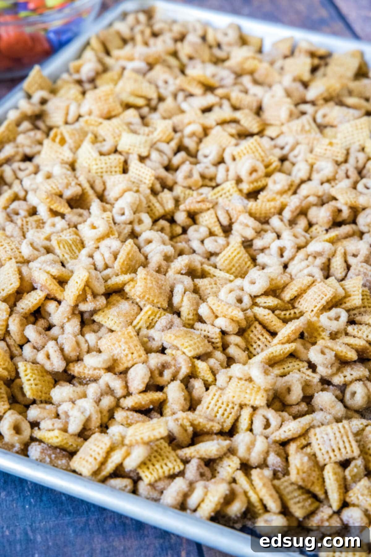 Cozy Pumpkin Spice Crunch 4 Pumpkin spice snack mix spread out on a parchment-lined baking sheet, glistening with its sweet coating.