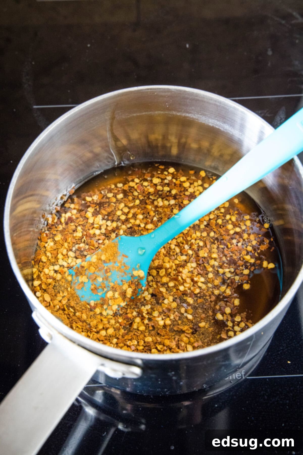 Make a hot honey chicken sandwich with crispy chicken coated with spicy honey, served between fluffy burger buns with cool and crunchy coleslaw! Hot honey in a saucepan with a rubber spatula.