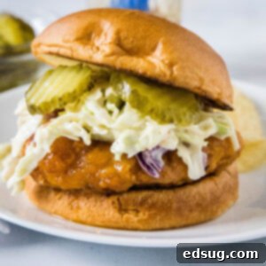 Crispy Honey Blaze Sandwich 2 A hot honey chicken sandwich topped with coleslaw and pickles on a white plate.