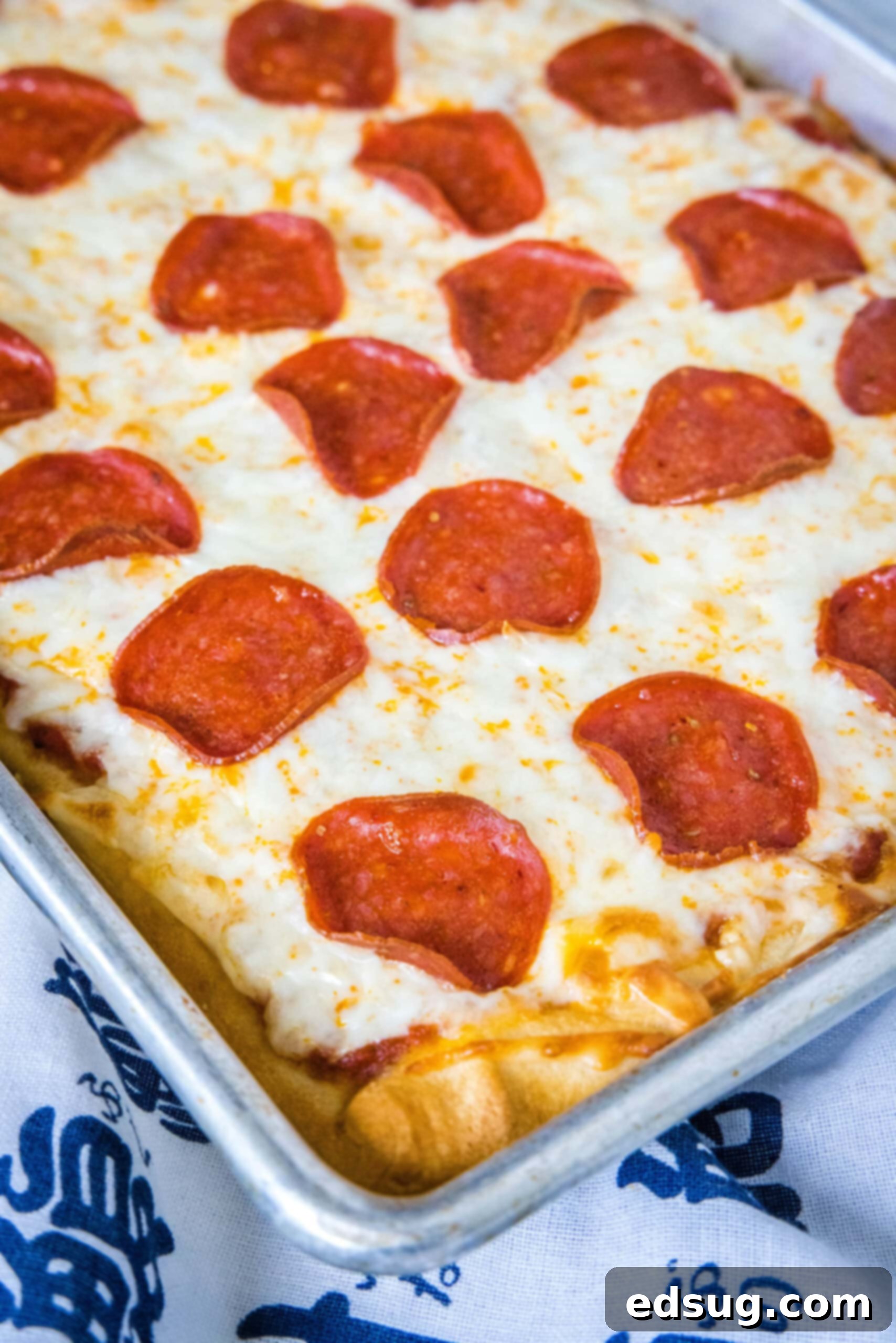 Cheesy crescent roll pizza is the perfect dinner or party snack! There’s zero kneading or rise time, just add your favorite toppings and bake! Pepperoni crescent roll pizza on a large rectangle baking sheet.