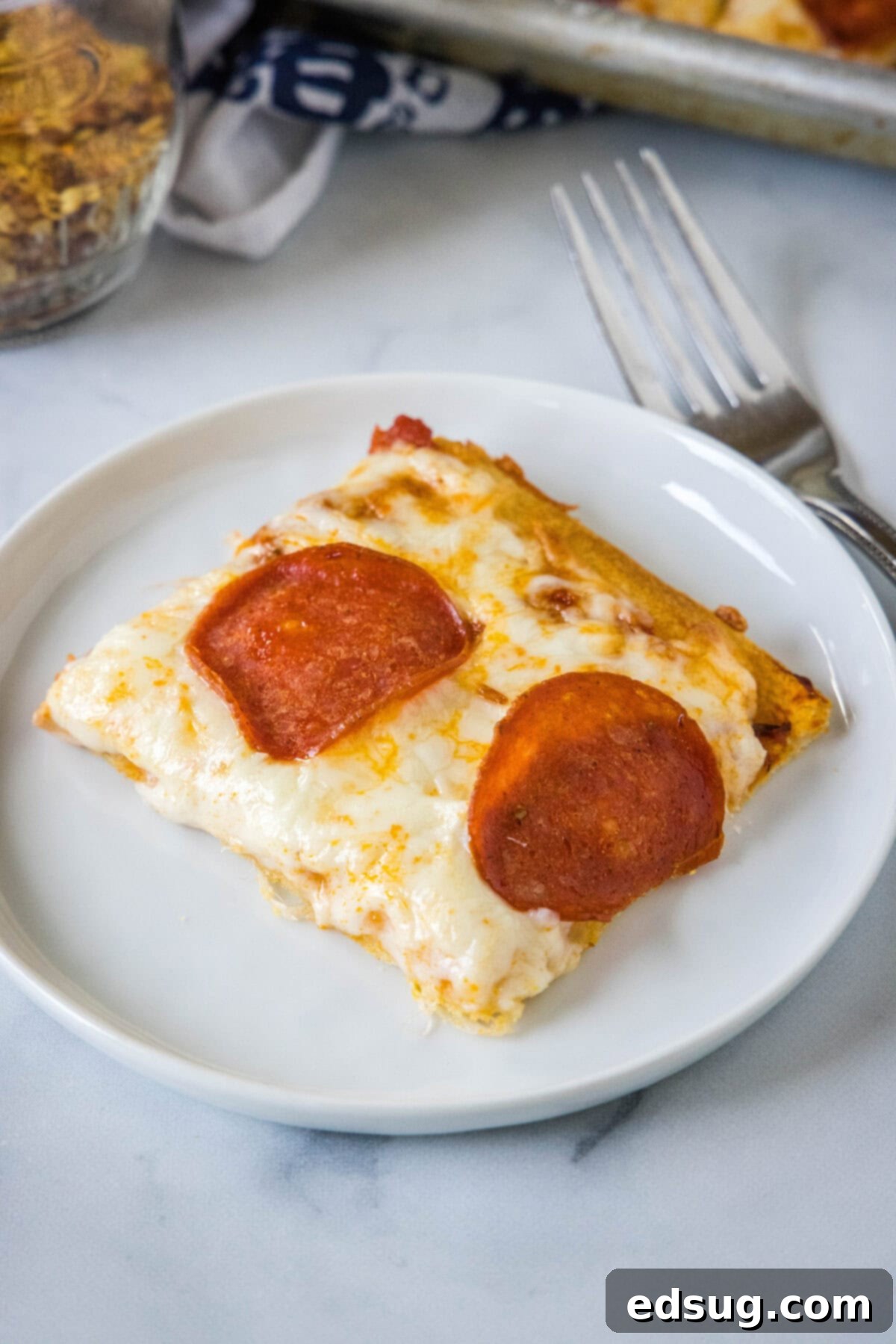 Cheesy crescent roll pizza is the perfect dinner or party snack! There’s zero kneading or rise time, just add your favorite toppings and bake! A slice of pepperoni crescent roll pizza on a white plate.