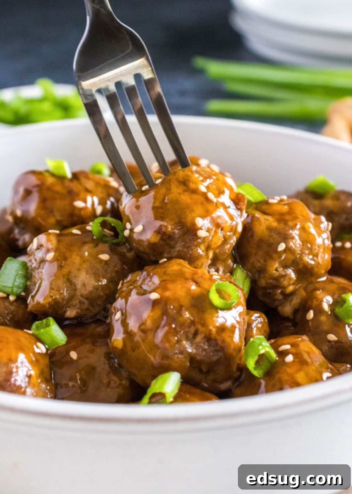 a fork serving korean meatballs from a white bowl