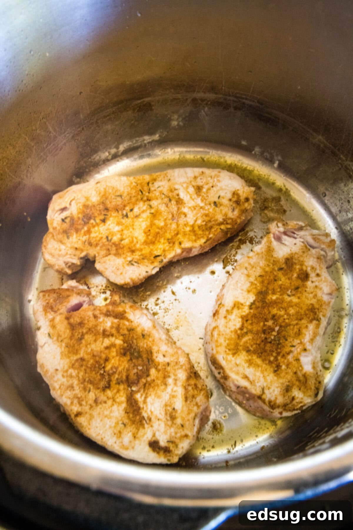 Instant Pot pork chops are perfectly seasoned, perfectly cooked, and so juicy! Pair these easy pork chops with a side of veggies or salad. Seasoned pork chops searing inside the instant pot, developing a golden-brown crust.