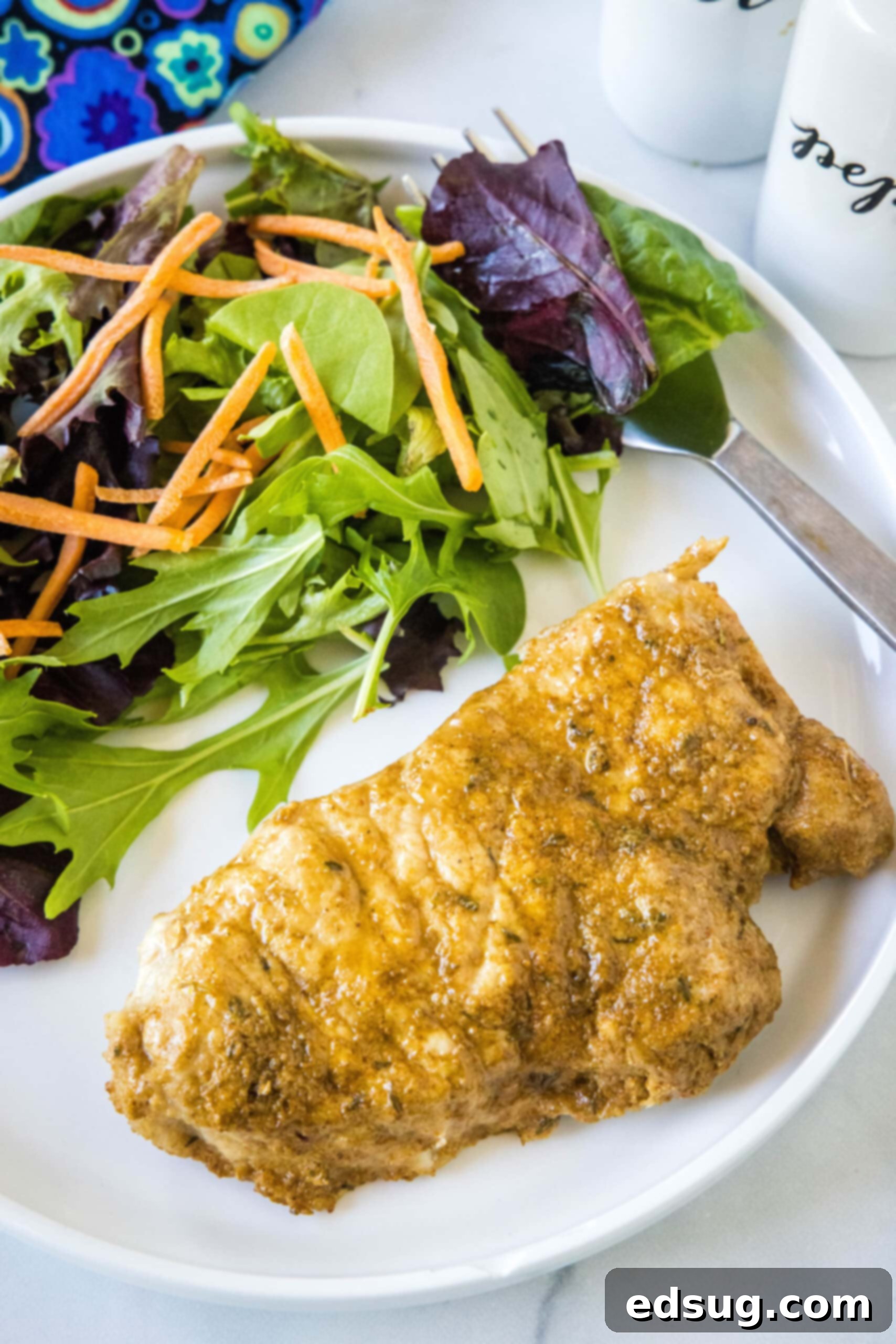 Instant Pot pork chops are perfectly seasoned, perfectly cooked, and so juicy! Pair these easy pork chops with a side of veggies or salad. An instant pot pork chop with a side of salad on a white plate, garnished beautifully.