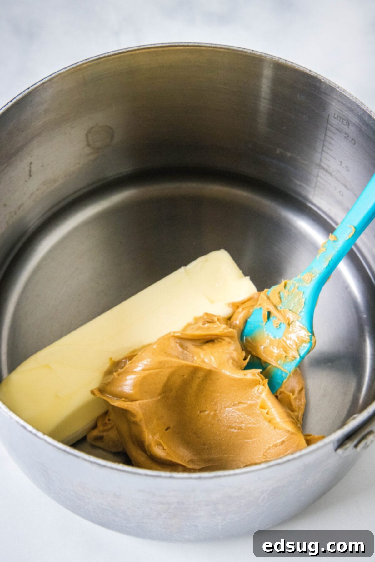 Creamy peanut butter and a stick of unsalted butter melting in a metal saucepan, ready to be incorporated into the cake batter.