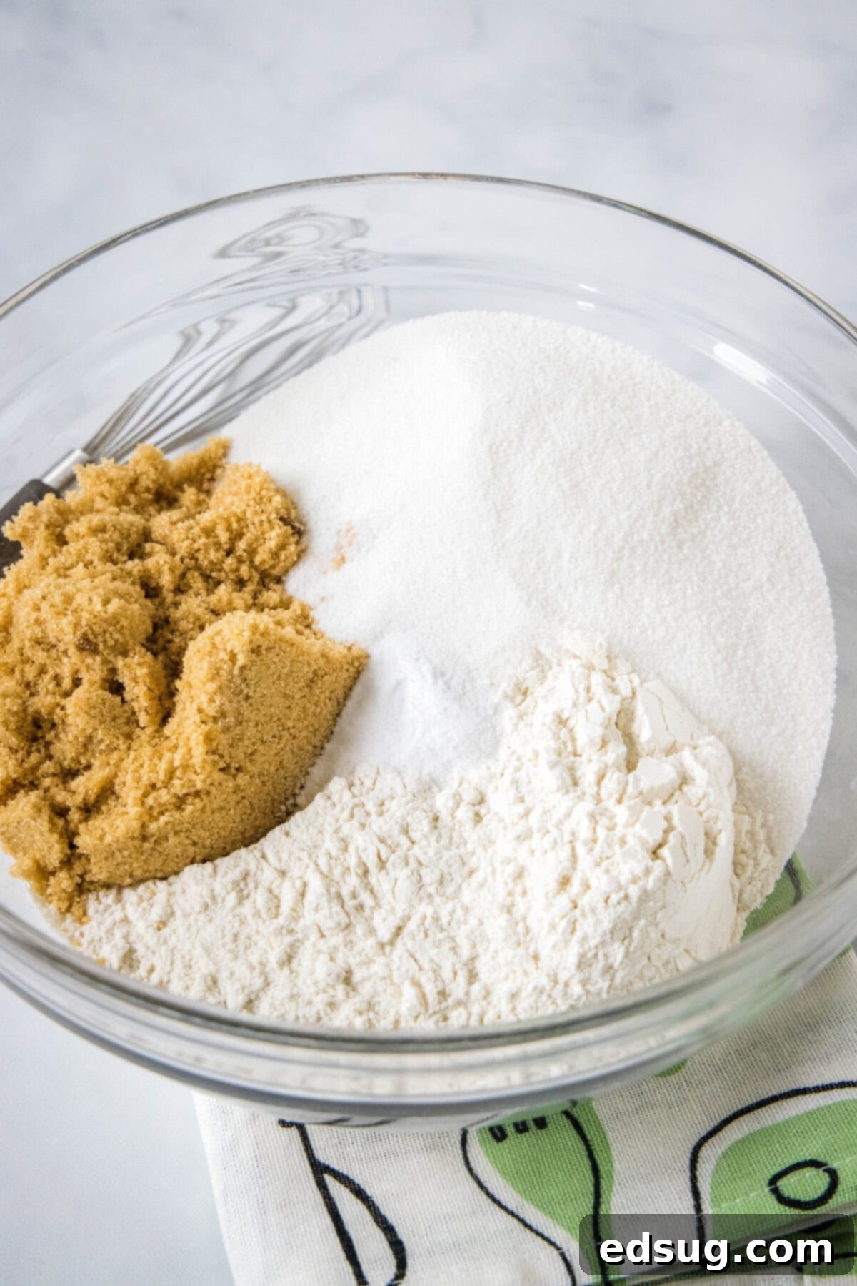 A glass bowl containing precisely measured dry cake ingredients, perfectly combined and ready for the wet ingredients.