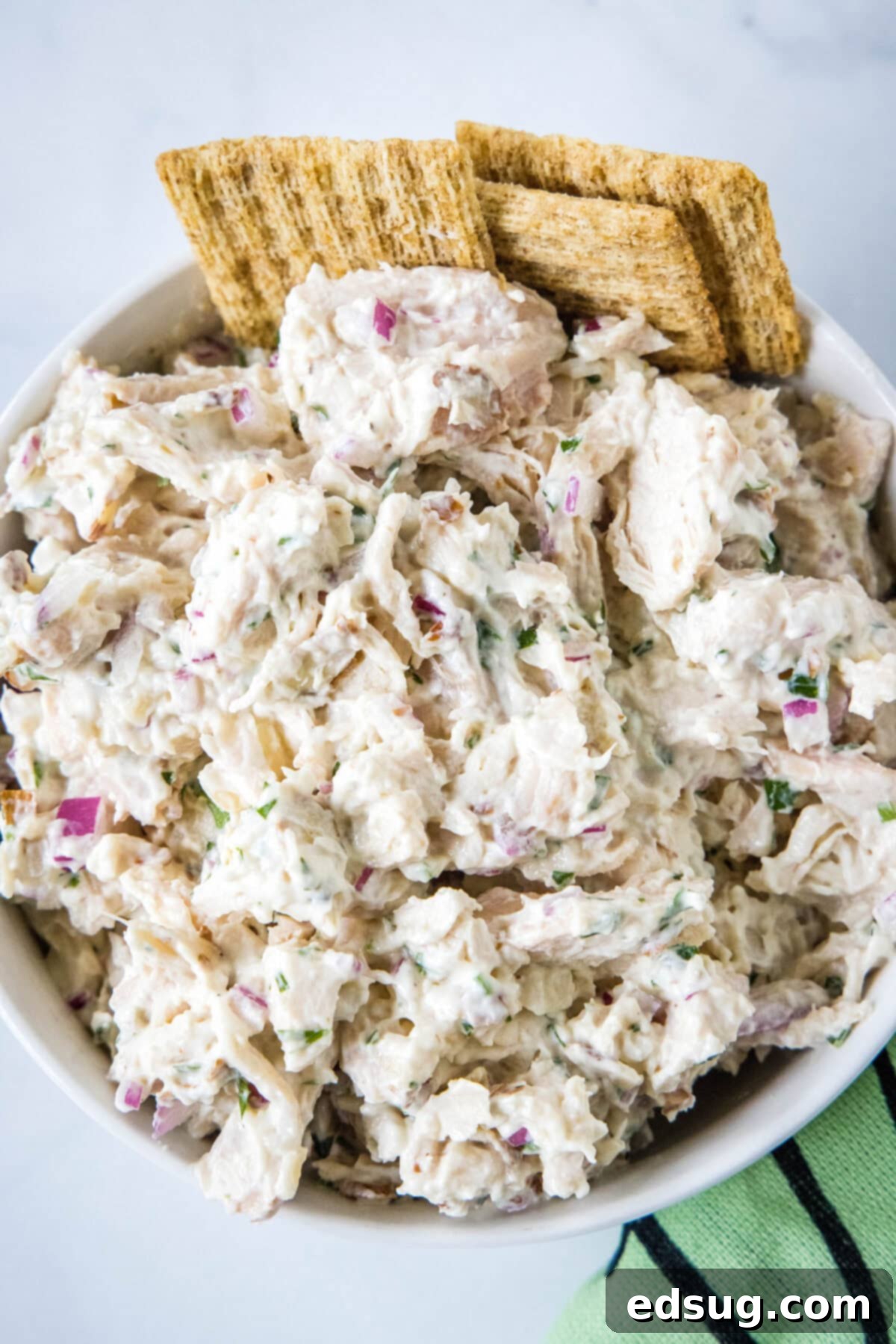 High protein Greek yogurt chicken salad in a elegant white bowl, garnished with fresh herbs, ready to be served.