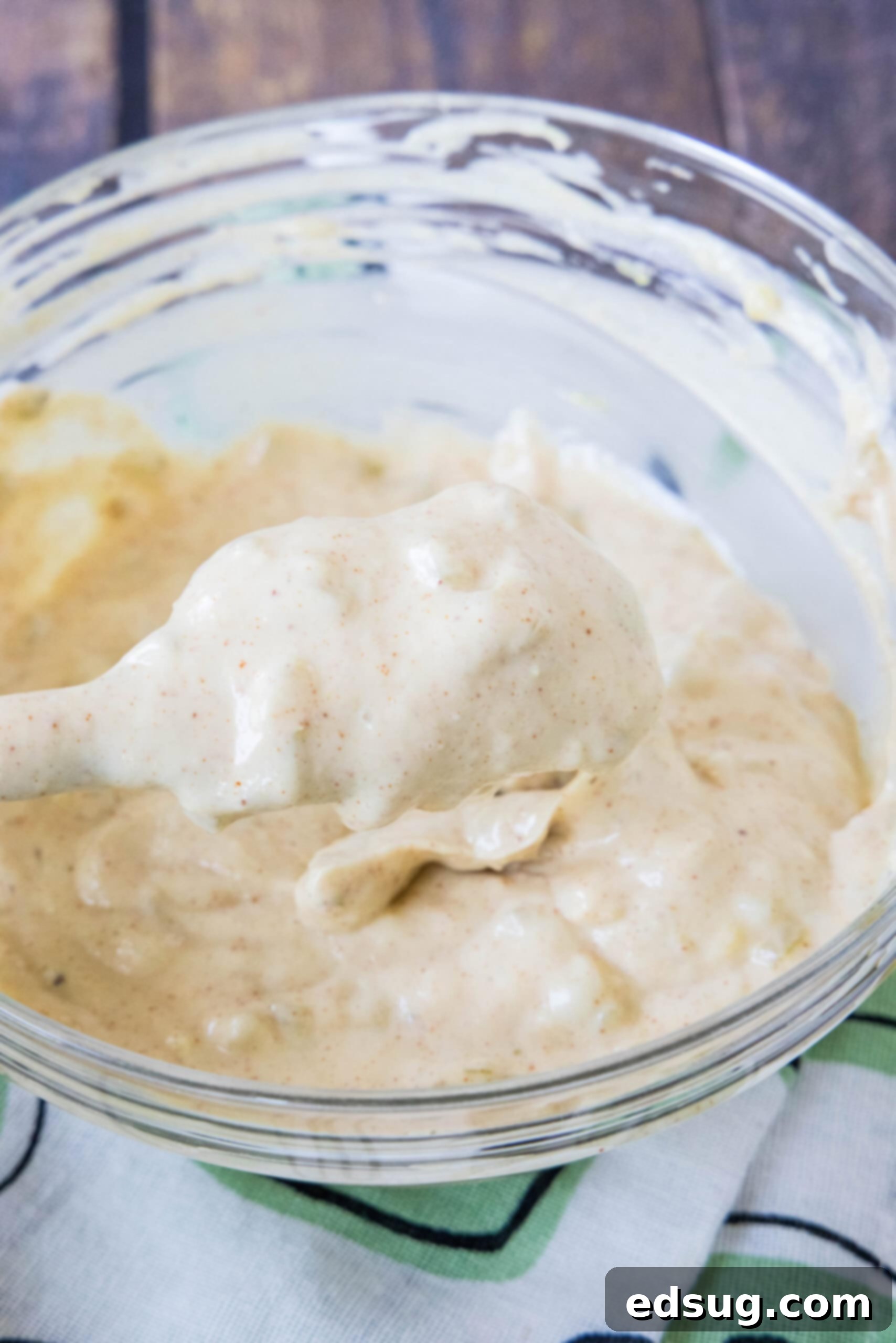 Close up of a spatula covered with Big Mac Sauce held over a bowl of sauce in the background.