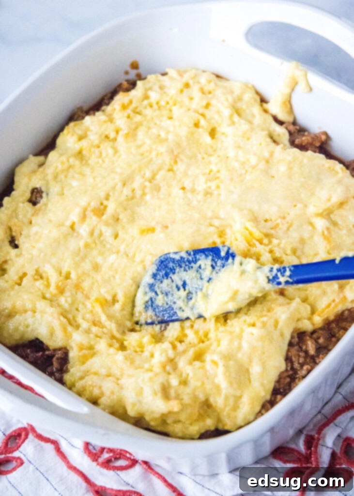 Hearty Sloppy Joe Cornbread Pie 4 Spreading cornbread batter evenly over the sloppy joe filling in a baking dish.