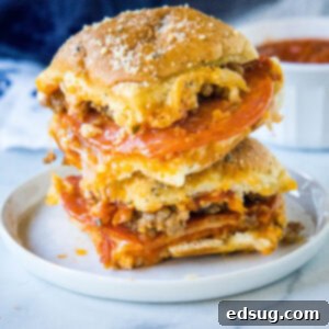 Two pizza sliders stacked on a white plate, showcasing the melted cheese and toppings.