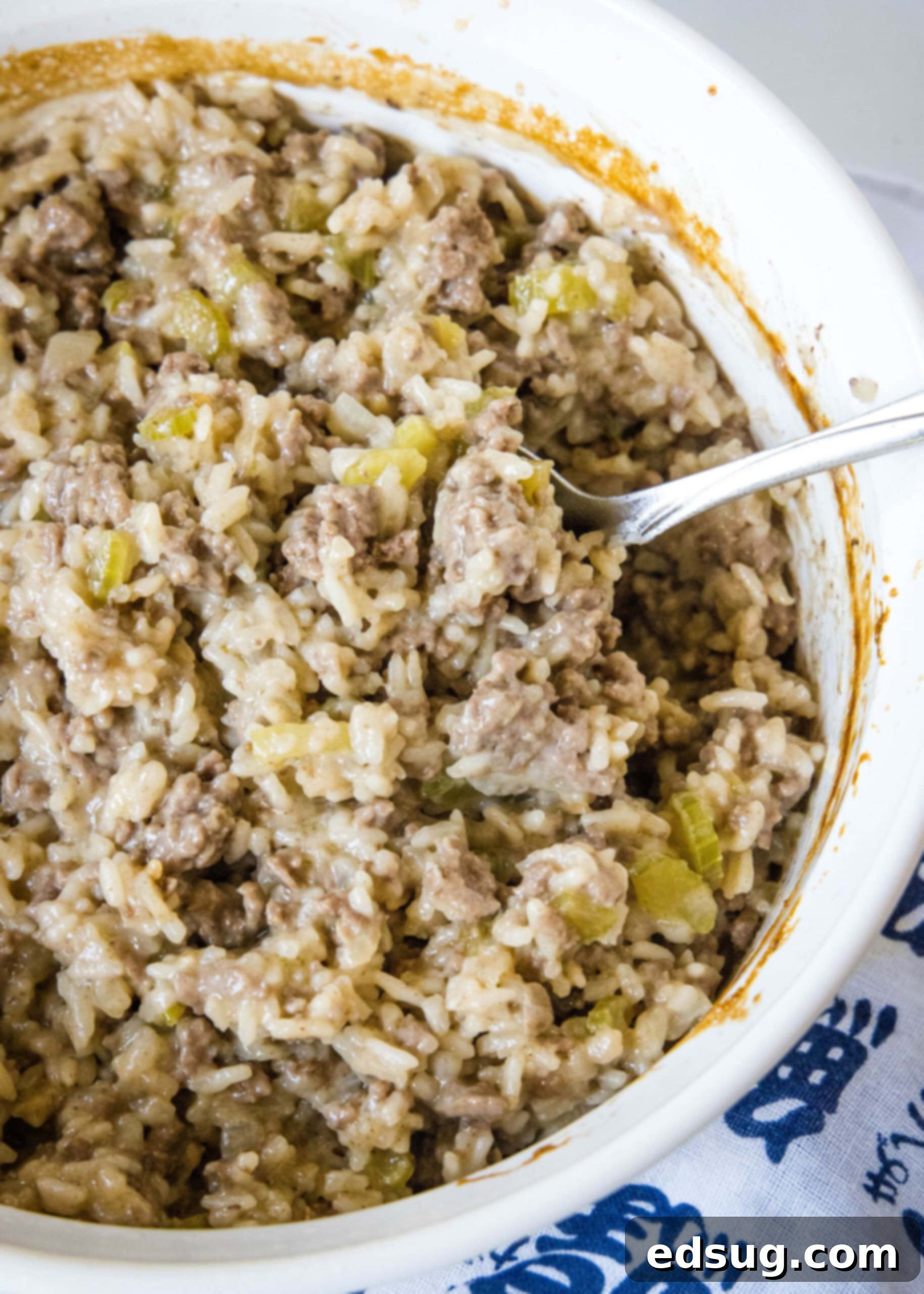 Hamburger rice casserole is an easy retro dinner recipe with fluffy rice, juicy ground beef, and veggies cooked in cream of mushroom soup! Hamburger rice casserole in a round casserole dish.