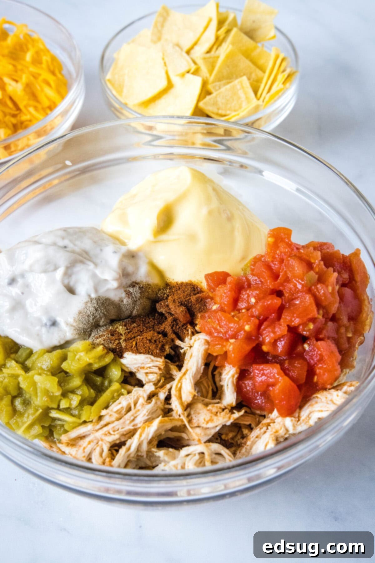 King Ranch chicken casserole ingredients combined in a glass mixing bowl, ready for assembly.