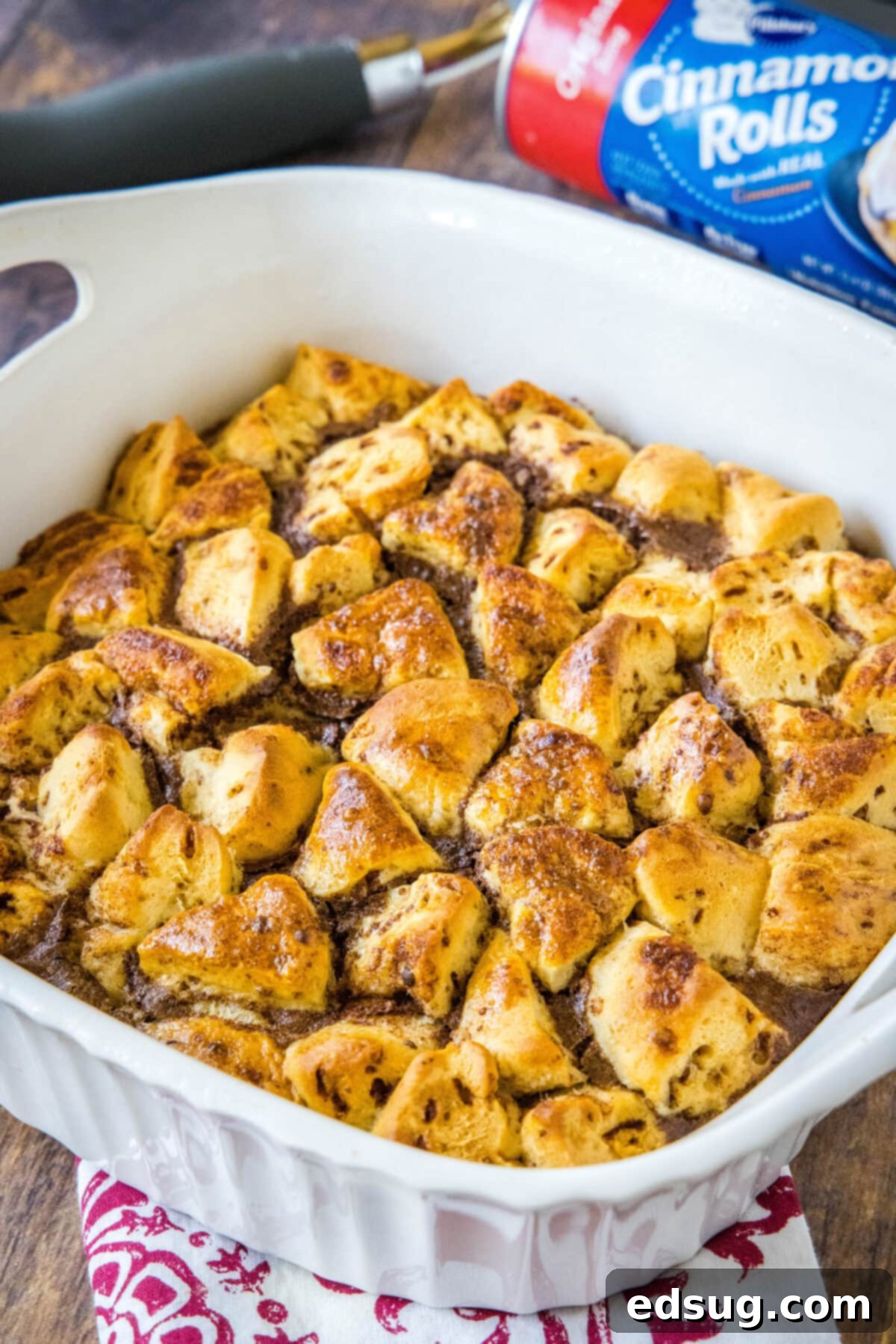 Cinnamon roll casserole is a quick and easy breakfast casserole with flaky layers baked in a rich and creamy custard. Perfect for a crowd! A freshly baked cinnamon roll casserole, golden brown and puffed, cooling slightly in a ceramic baking dish after being removed from the oven.