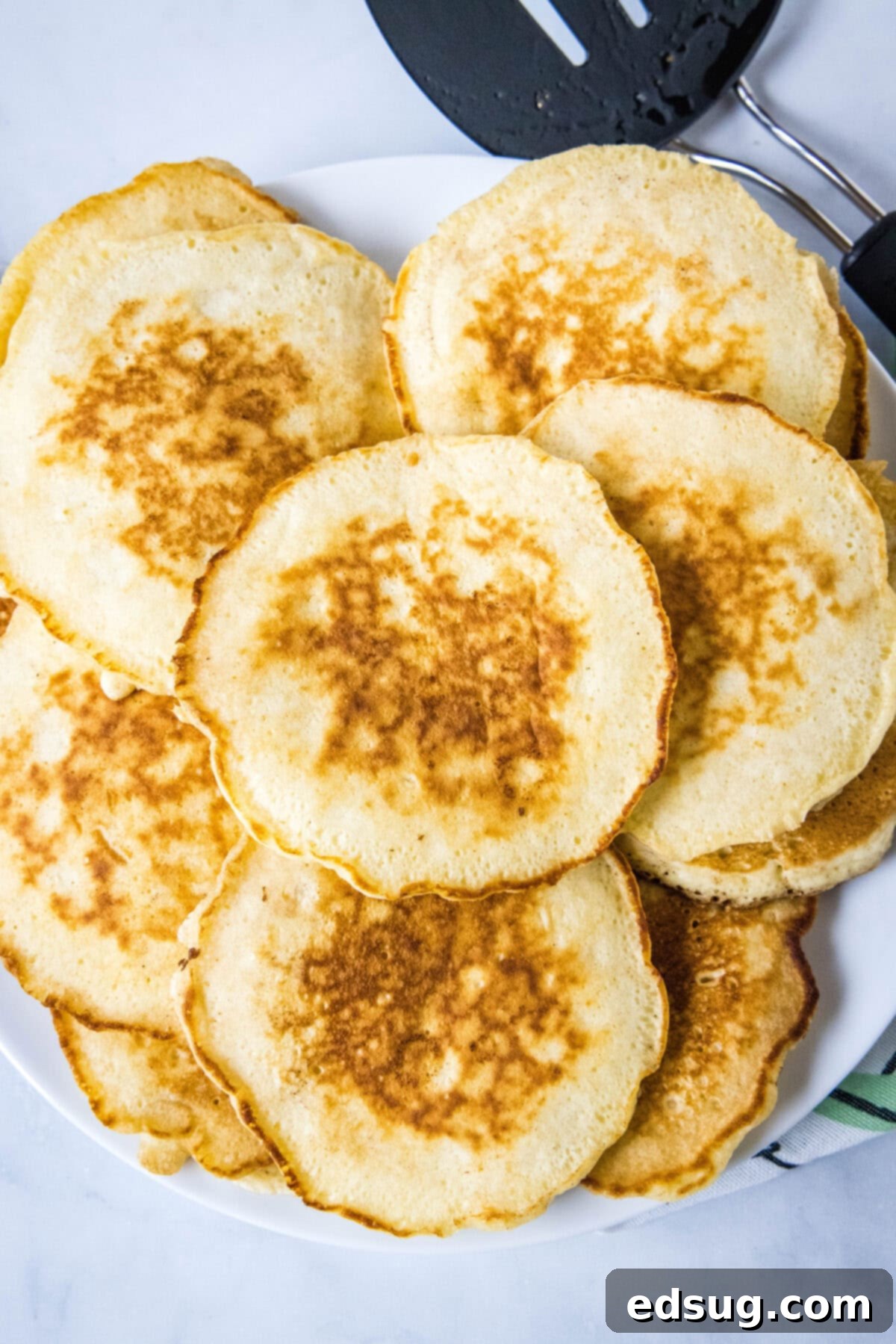 An overhead shot of a platter piled high with golden-brown griddle cakes, ready for serving.
