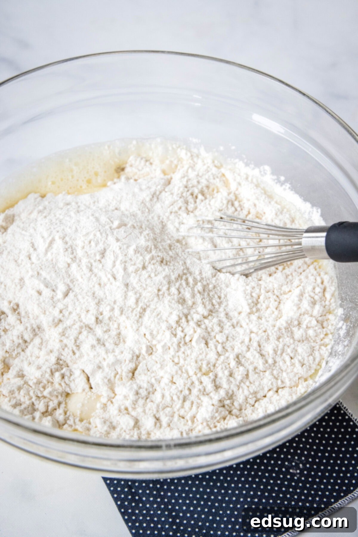 Griddle cake batter ingredients combined in a glass mixing bowl, showcasing the consistency of the batter.