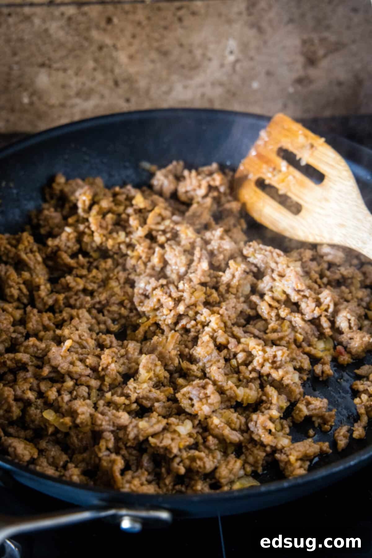Sausage and onions browning in a skillet for pasta risotto. Ground Italian sausage and finely chopped onions browning in a large skillet, releasing aromatic steam.