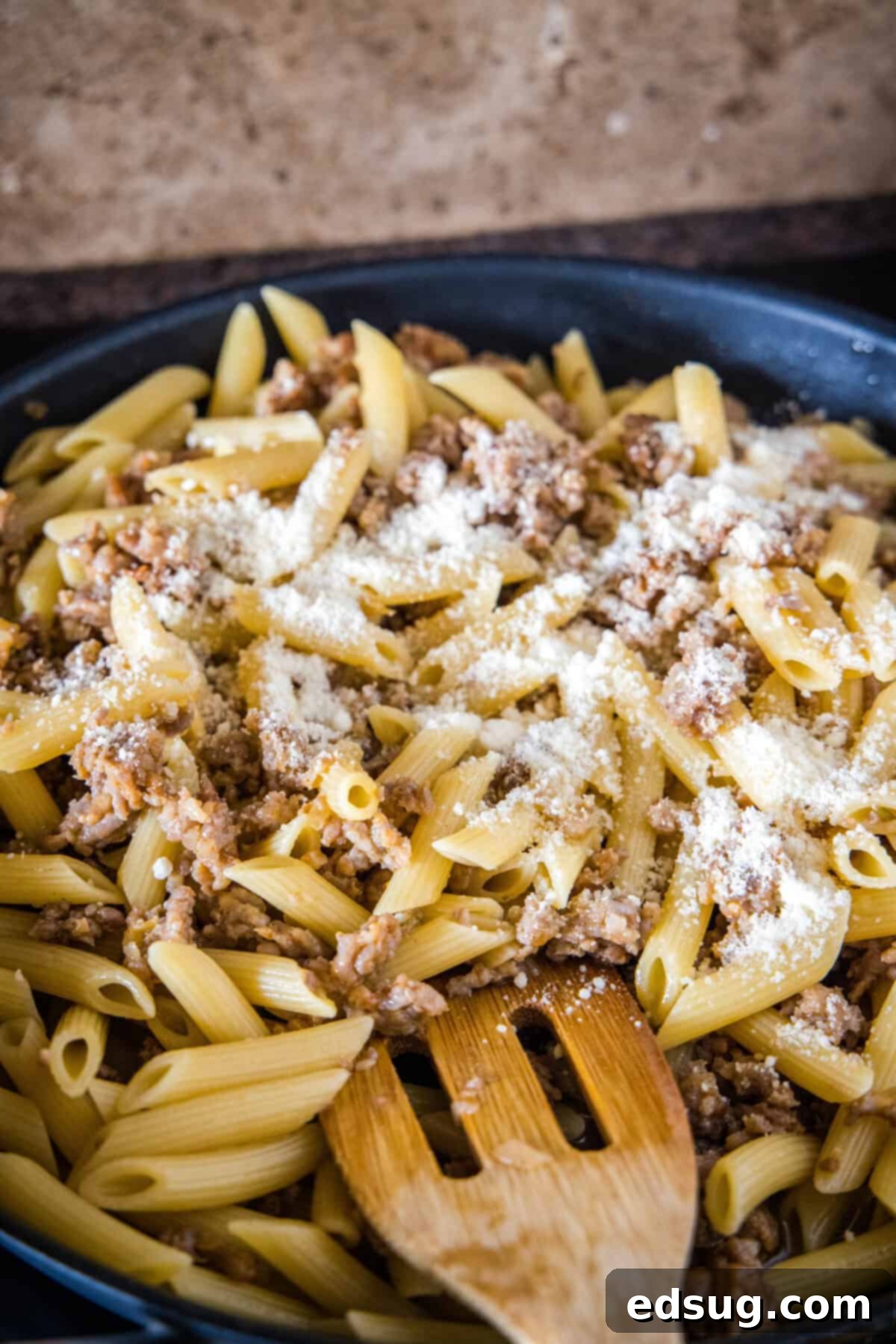 Finishing pasta risotto with Parmesan cheese. Freshly grated Parmesan cheese being stirred into creamy pasta risotto in a skillet with a wooden spoon, completing the dish.
