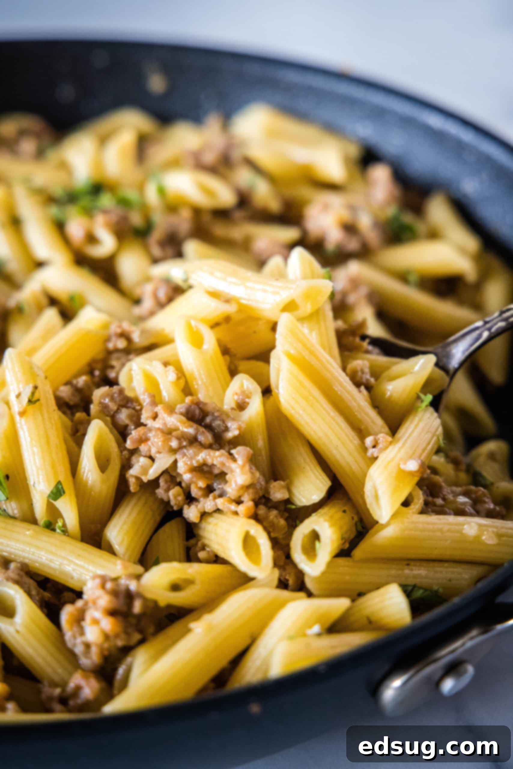 Close-up of Pasta Risotto cooking. A close-up shot of the creamy pasta risotto simmering in a skillet, capturing the steam and rich texture of the sauce and penne.