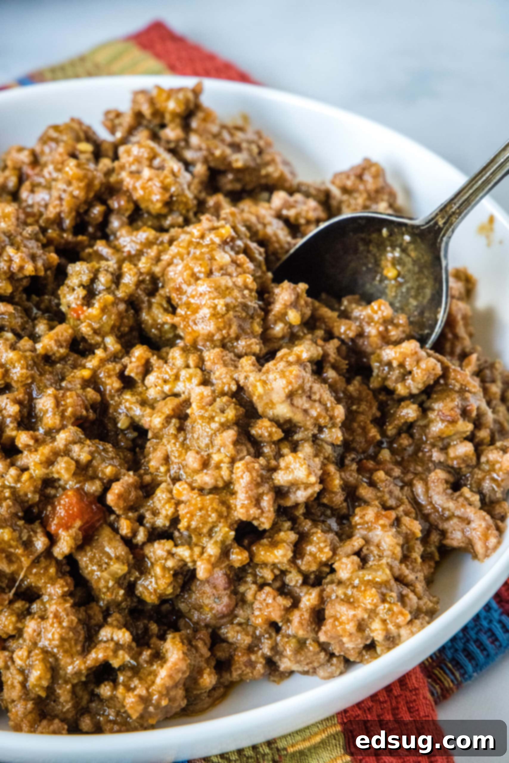 Note that while it’s fine to put raw meat in the slow cooker, you should never add frozen meat to the slow cooker before it’s thawed. Frozen meat stays at an unsafe temperature for too long in the low heat, risking the growth of bacteria. If you have frozen ground beef, be sure to thaw it completely before you use it. A large white bowl brimming with slow cooker taco meat, a serving spoon nestled in, ready for a gathering.