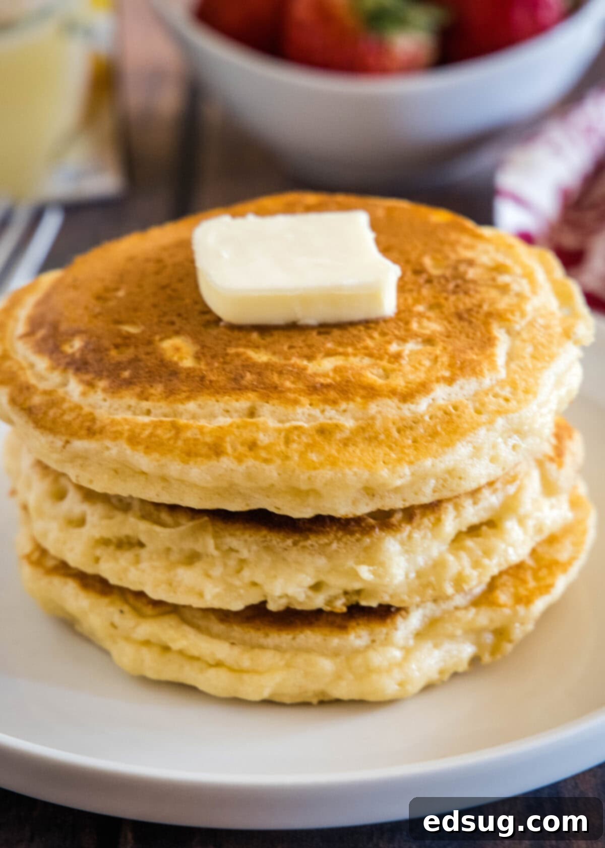 Creamy Spiced Eggnog Pancakes 5 A perfectly stacked pile of fluffy eggnog pancakes on a white plate, ready to be served.