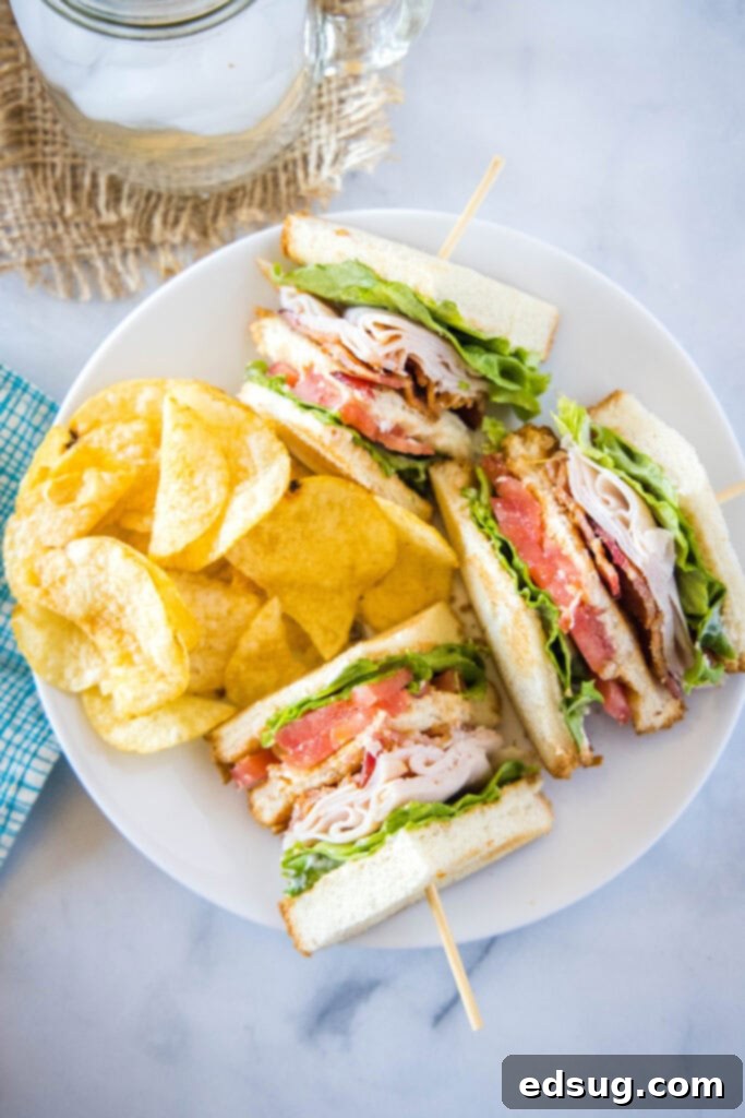 Ultimate Turkey Club Sandwich 5 turkey club sandwich on a white plate with potato chips