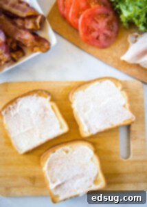 Ultimate Turkey Club Sandwich 8 toasted bread with mayo on a cutting board