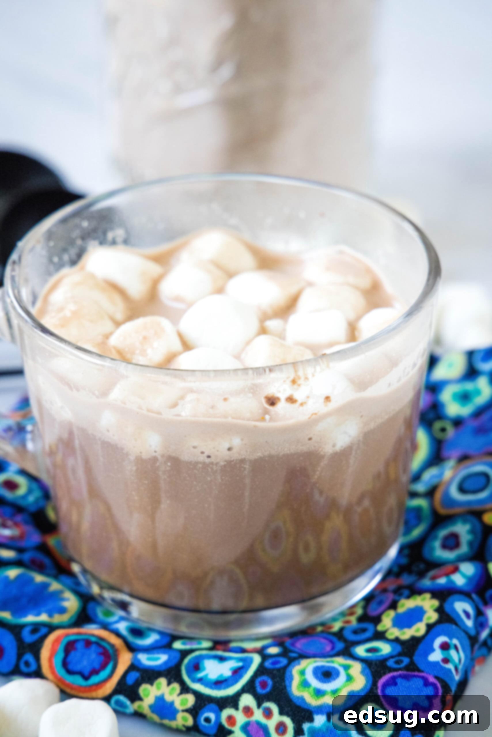 Hot chocolate in a clear mug topped with mini marshmallows.