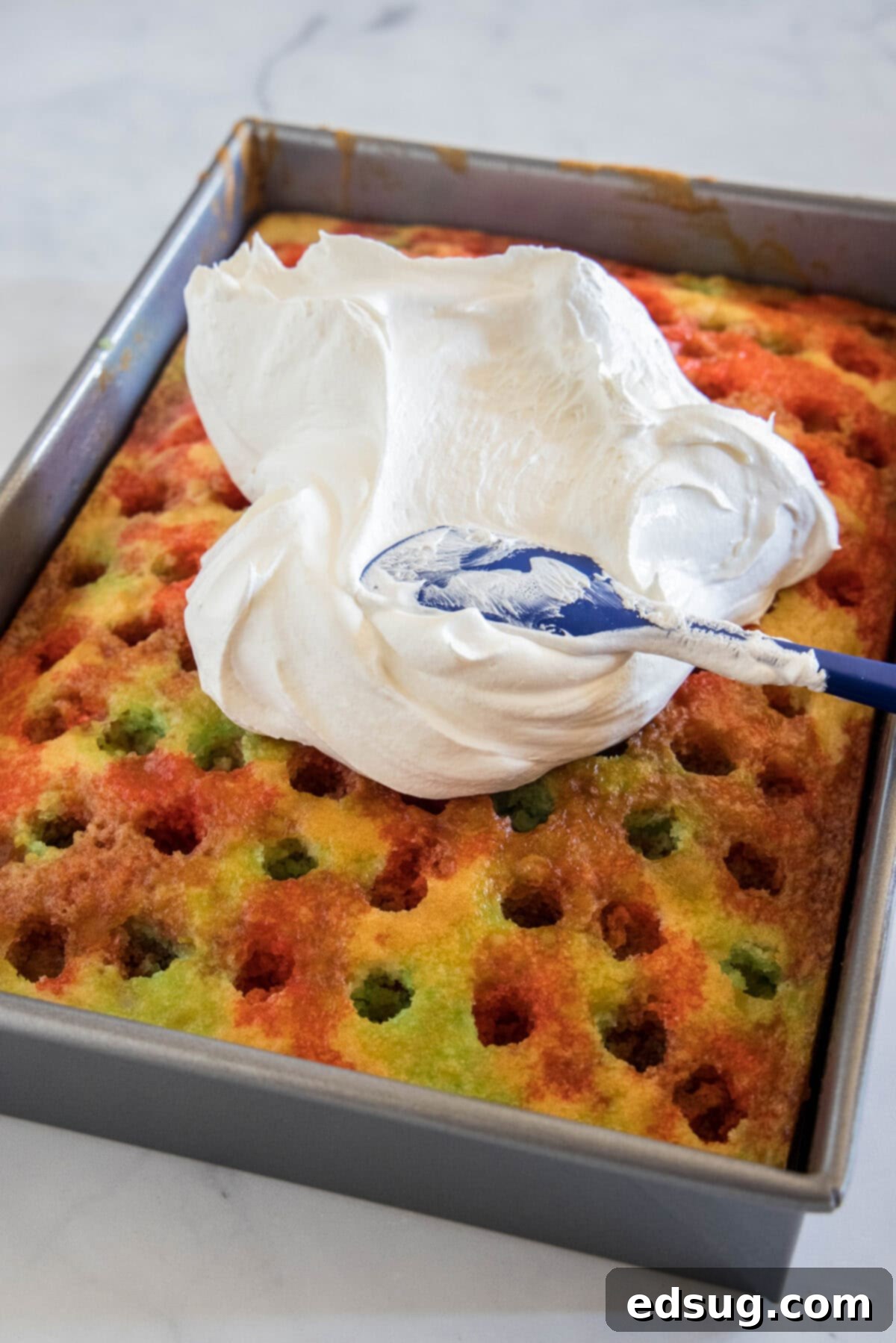 Holiday Hidden Gem 5 spreading whipped topping on poke cake