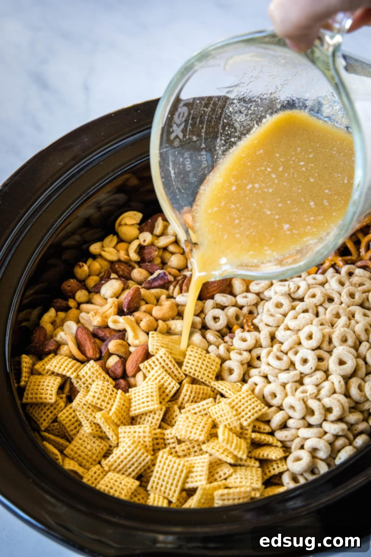Crock-Pot Party Crunch 4 pouring butter mixture over chex mix in crock pot
