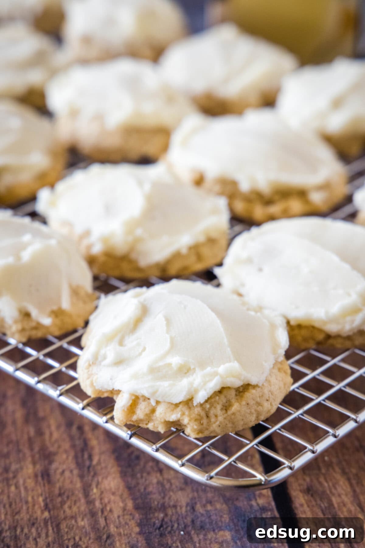 Festive Eggnog Cookies 5 frosted eggnog cookies cooling on a wire rack, sprinkled with a touch of nutmeg.