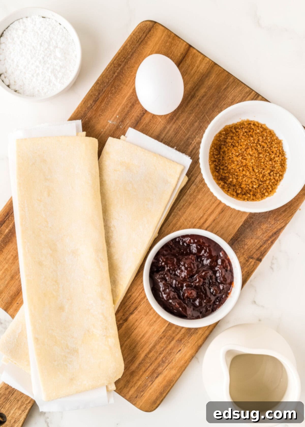 Holiday Swirl Pastry Tree 3 A visual display of all the simple ingredients required to make a delicious puff pastry Christmas tree, including puff pastry sheets, strawberry jam, and other baking essentials.