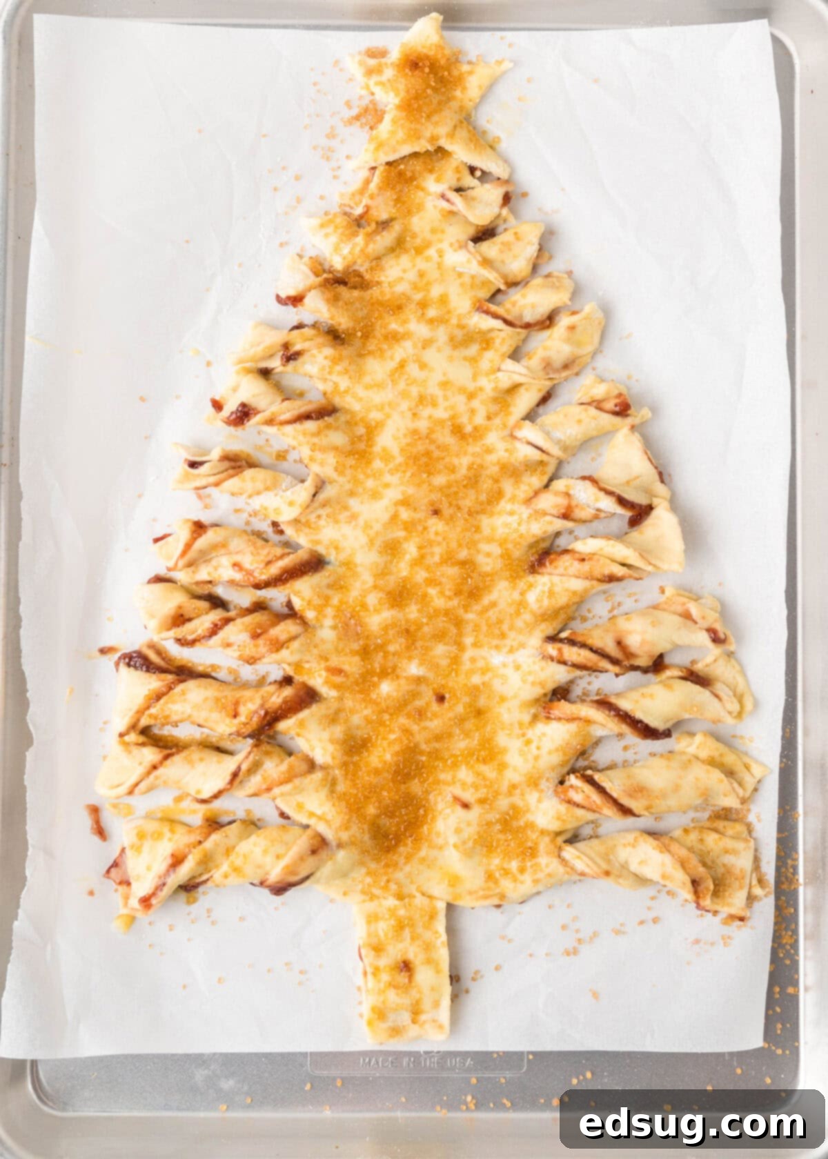 Holiday Swirl Pastry Tree 8 Raw sugar generously sprinkled over the unbaked puff pastry Christmas tree, ready for the oven to achieve a golden, crunchy topping.