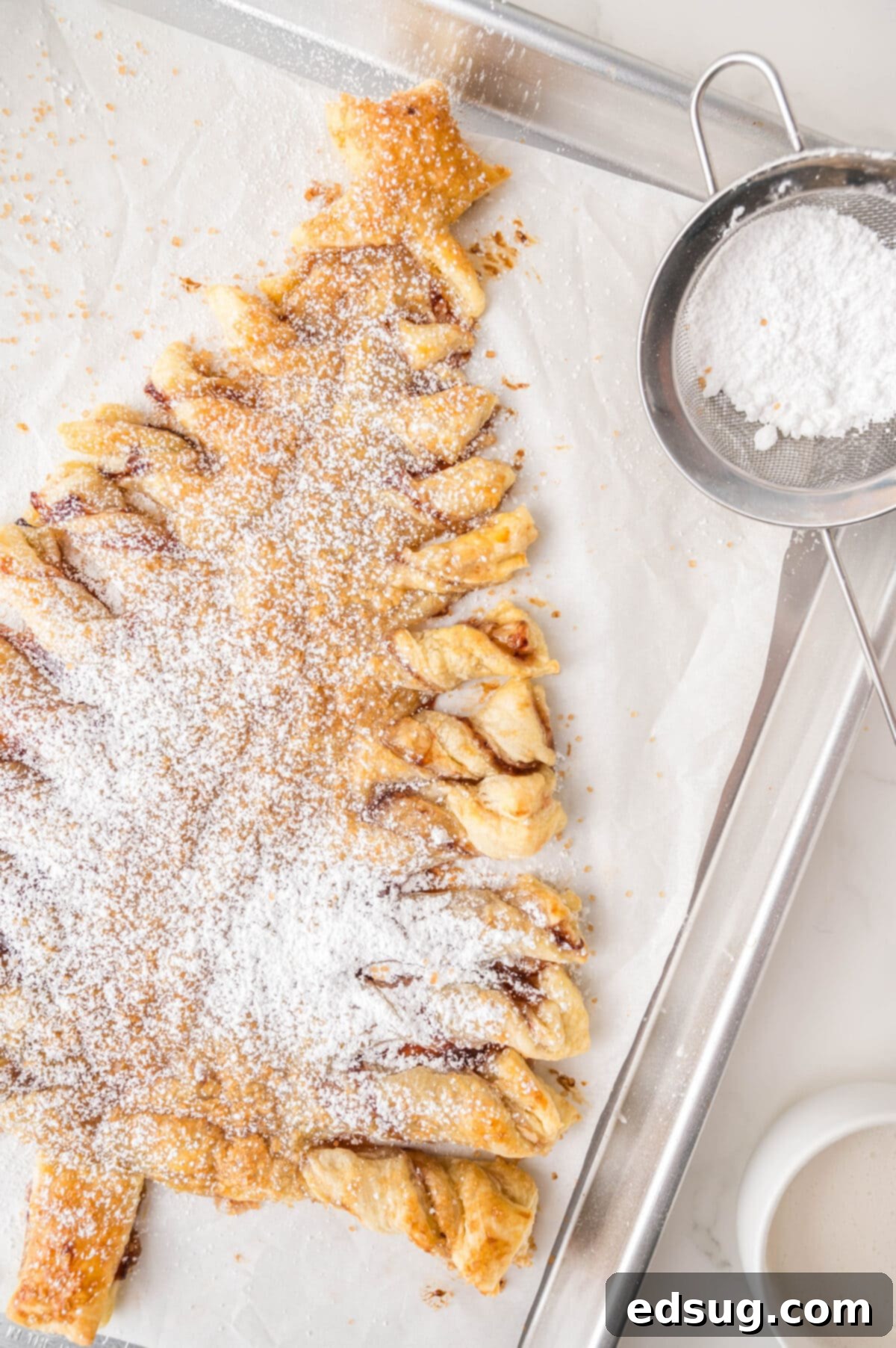 Holiday Swirl Pastry Tree 10 A close-up view of the baked puff pastry Christmas tree, beautifully dusted with powdered sugar, highlighting its flaky layers.